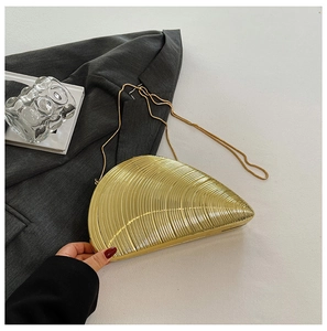 Macro shot of gold shell-shaped evening bag featuring radial stripes and a sleek snake chain