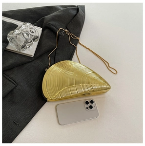 Close-up of gold shell clutch bag with metallic texture and thin chain strap