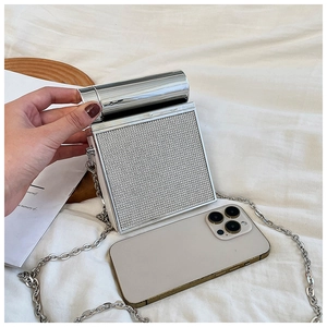 Silver square hard shell box bag next to phone showing compact mini size and metal mesh