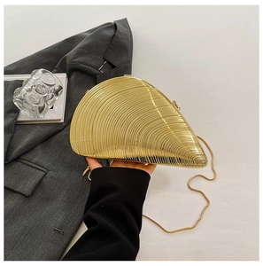 Close-up of golden shell evening bag with radial texture and a slim metal chain strap