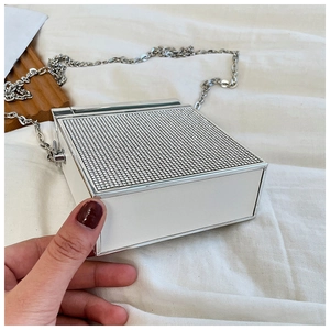 Close-up of sparkling rhinestone top and silver metal edging on white box evening bag