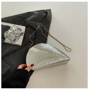 Macro view of silver conch shell clutch with metallic ridges and snake chain