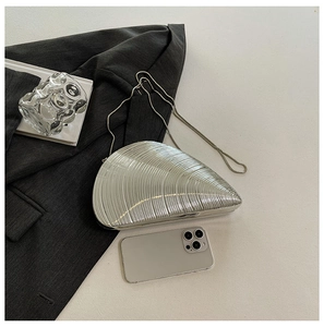 Detailed view of shell-shaped silver acrylic evening clutch with metallic chain strap