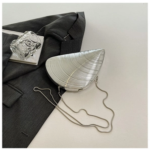 Macro shot of silver conch-shaped shell evening clutch with metallic texture and chain
