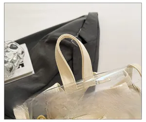 Detail of clear PVC tote bag showing white canvas handles and reinforced gold metal eyelets