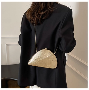 Detailed close-up of a gold seashell clutch bag with fine metallic radial stripe textures