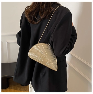 Detailed view of a gold shell-shaped clutch bag with textured finish and chain strap