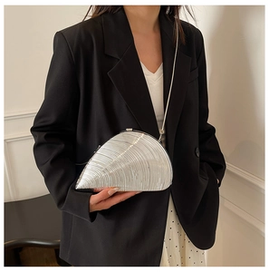 Detail of silver shell-shaped acrylic clutch bag with metallic texture and chain strap
