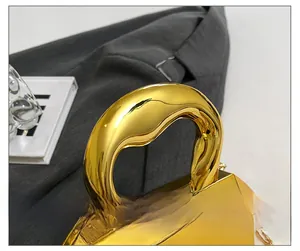 Close-up of gold mirror acrylic bag with arc handle and geometric cut details