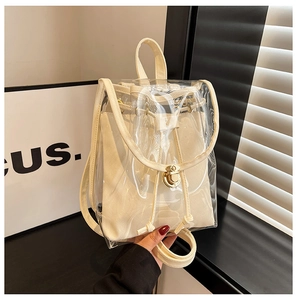Detail view of transparent PVC backpack with beige canvas inner bag and golden twist lock