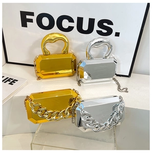 Close-up of geometric acrylic clutch bags with chunky chains in gold and silver finish