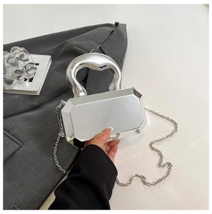 Close-up of a silver mirror acrylic clutch bag with geometric cut and thick metal handle