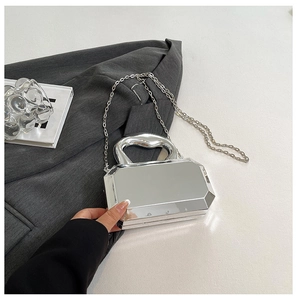 Macro view of silver mirror acrylic box bag with metallic texture and curved top handle
