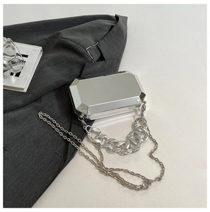 Close-up of silver octagonal mirror box bag with chunky chain handle on suit fabric