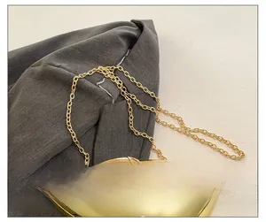 Detail shot of sleek gold metallic mango clutch bag with a fine chain shoulder strap