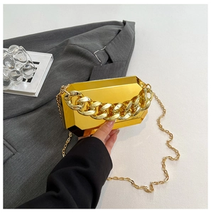 Detailed view of golden geometric acrylic evening clutch with dual chain straps and handle