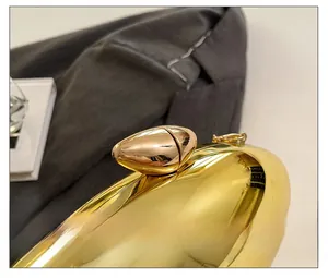 Detailed macro view of the golden pebble-shaped metal clasp and chain link of the evening bag