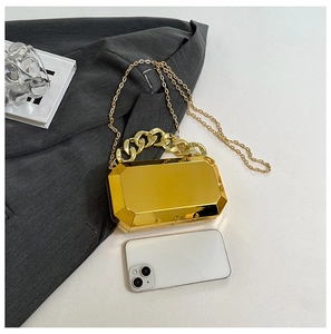 Compact gold mirror acrylic clutch bag shown with a smartphone for scale reference
