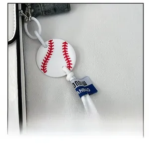 Detail of baseball charm with red stitching and branded tag on white textured bag