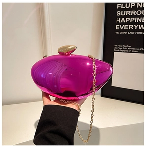 Detail of fuchsia acrylic evening bag with gold chain and high-gloss metallic finish