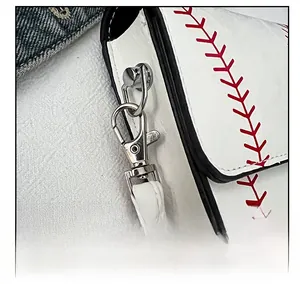 Macro detail of silver hardware and red baseball stitching on white leather bag