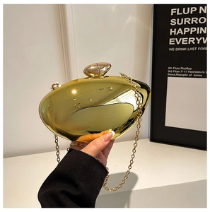 Detail of a shiny gold oval acrylic clutch bag with a polished mirror finish and chain