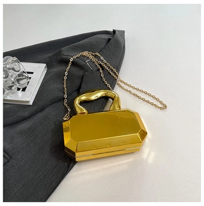 Close-up of golden geometric mirrored box bag with acrylic handle and chain strap