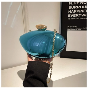 Detail of teal acrylic clutch bag with glossy metallic finish and gold chain strap