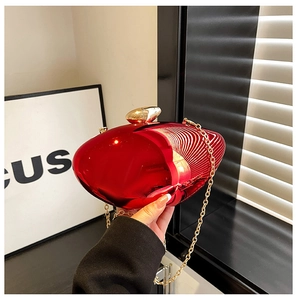 Detail of red mirror acrylic heart bag with gold pebble clasp and chain shoulder strap