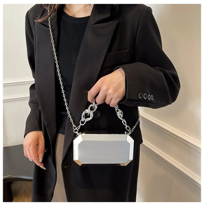 Detail view of octagon silver acrylic clutch bag with chunky chain handle on model