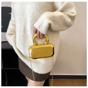 Detail shot of golden geometric evening bag with thick handle and mirror finish