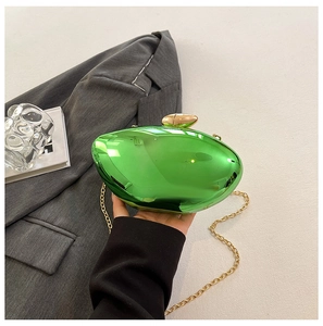 Detail of emerald green acrylic clutch bag with glossy mirror finish and gold chain strap