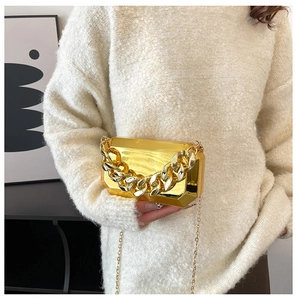 Close-up of gold mirror acrylic box bag with chunky chain detail and metallic strap
