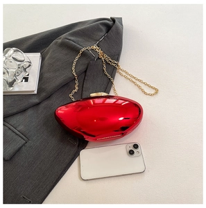 Macro view of metallic red evening clutch bag with gold chain strap and smartphone reference