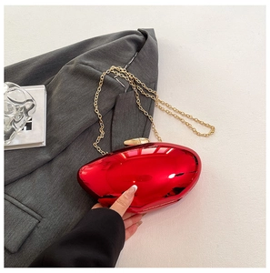 Close-up of glossy red acrylic geometric clutch with gold spherical clasp and chain