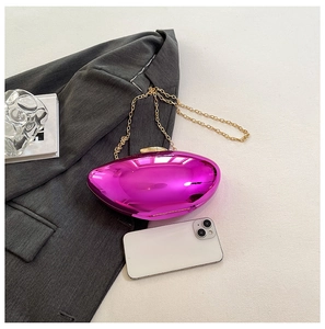 Close-up of bright pink acrylic evening bag with gold chain strap and smartphone for scale