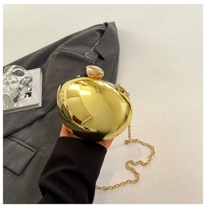 Close-up of golden pebble-shaped evening bag with ball clasp and thin metal chain strap