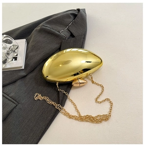 Close-up of golden shell acrylic evening bag with metallic chain on a grey blazer