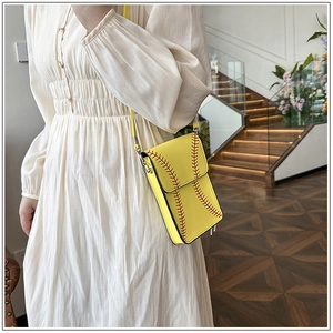Detail of yellow baseball-themed crossbody bag with red stitching and slim strap