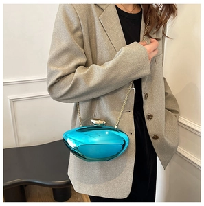 Detail of turquoise metallic acrylic clutch with gold chain and pebble-shaped design