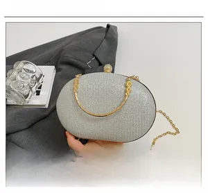 Detail of silver glitter evening bag with gold floral handle and rhinestone clasp