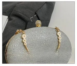 Detail of silver sequin clutch bag with floral embossed handle and diamond-encrusted clasp