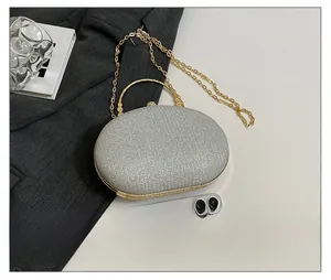 Detailed view of silver sequin evening bag with gold handle and chain strap on white background