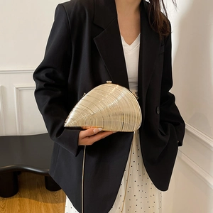 Golden conch shell evening bag with metallic finish and chain strap worn by a model