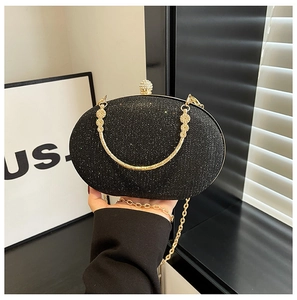 Detail of black glitter evening clutch featuring a gold ring handle and sparkly texture