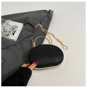 Macro detail of black glitter oval evening clutch with gold ring handle and chain strap