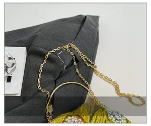 Detail of gold chain strap with yellow sequin embroidery and white beads on evening bag
