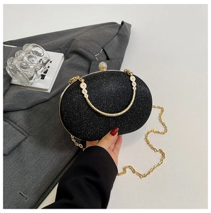 Detail of black glitter evening clutch with gold metal frame and pearl rhinestones