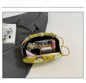 Detail view of the yellow embroidered evening bag showing interior capacity for essentials
