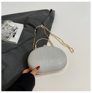 Detail of silver glitter clutch bag with gold curved handle on gray blazer